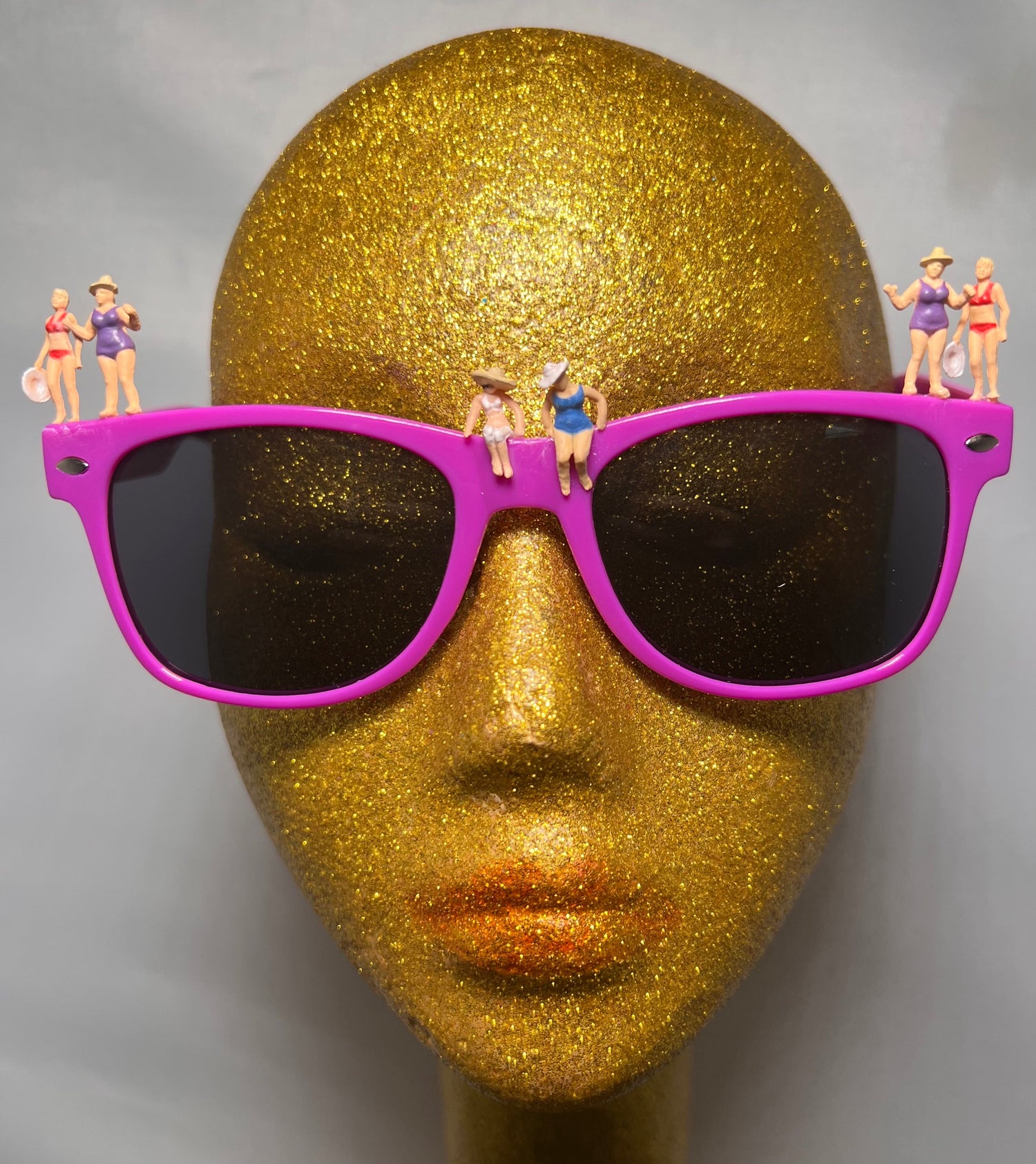 face with purple glasses with tiny little figures of people on them in swimsuits